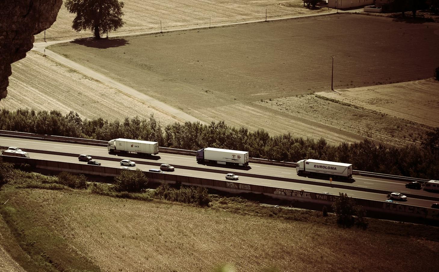 trail photography of running vehicles on street between grass field